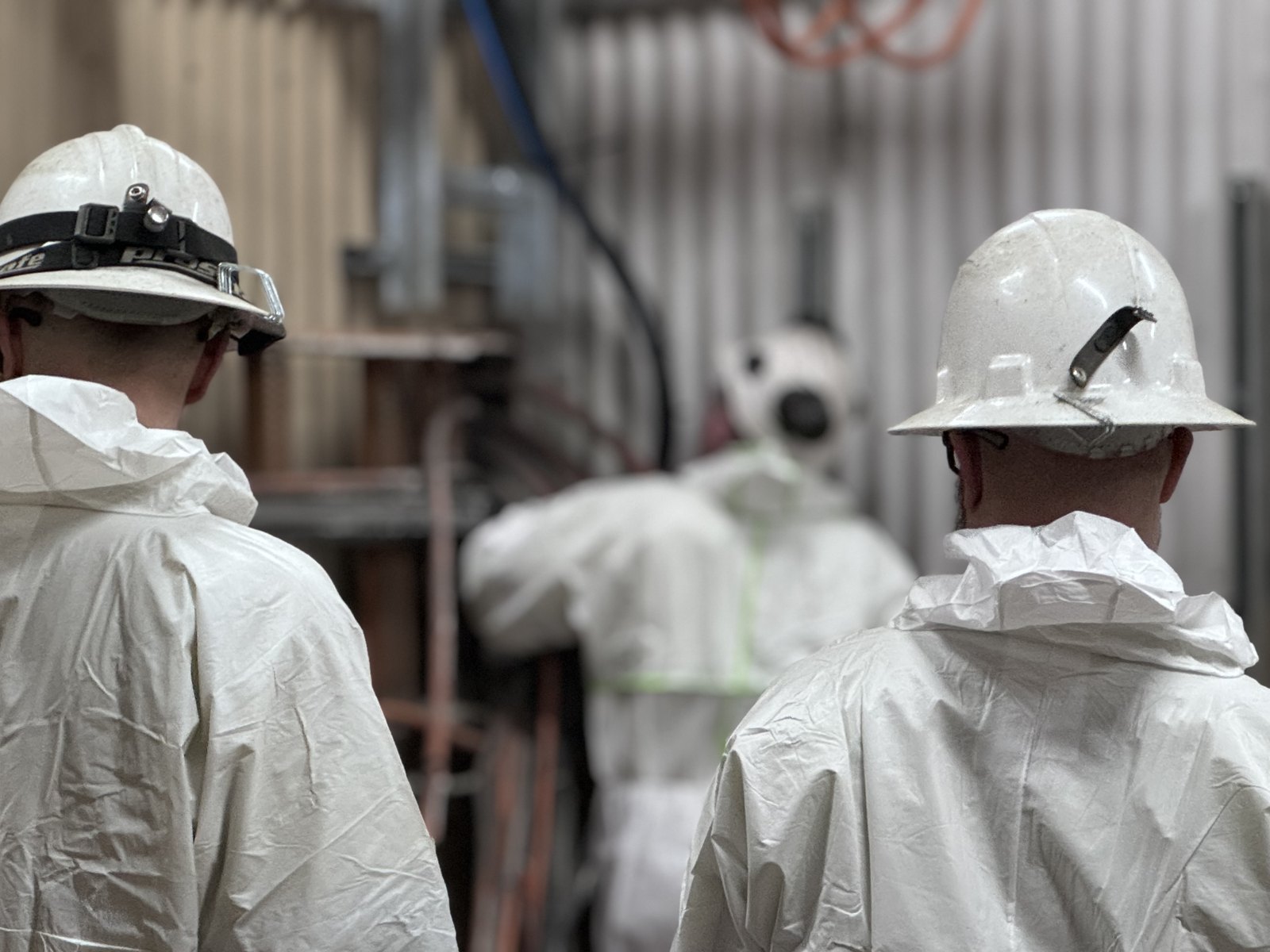 Crew in hard hats and disposable coveralls on site